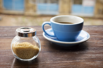 Brown sugar in a glass bowl and cup of coffee
