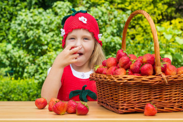 A funny little girl 4 years old with a basket of strawberries