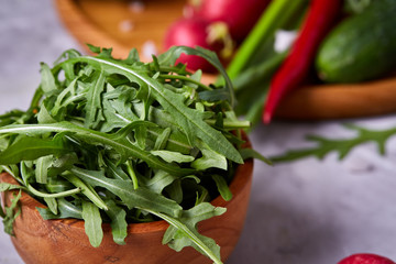 Creative fresh vegetable salad with ruccola, cucumber, tomatoes and raddish on white plate, selective focus