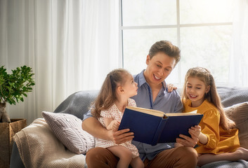 father reading a book to his daughters