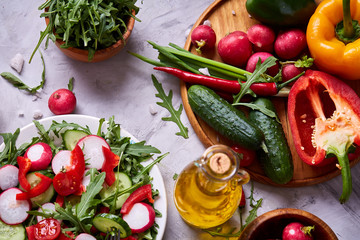 Creative fresh vegetable salad with ruccola, cucumber, tomatoes and raddish on white plate, selective focus