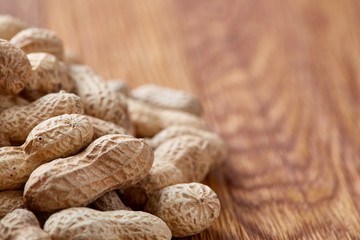 Unpeeled peanuts on a wooden background, top view, selective focus, shallow depth of field.