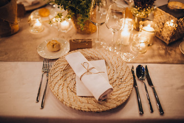 on festive table in wedding banquet area are plates, glasses, candles, cutlery, the table is...