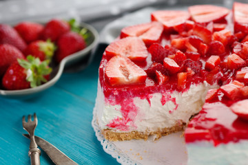 Homemade dessert cake of strawberry red fruit on blue wooden background with knife and fork