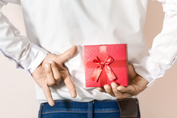 Young man hiding red gift box behind his back