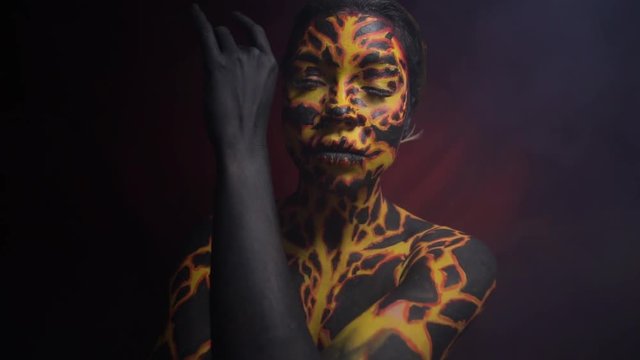 Body painting on the body of a girl in the form of volcanic lava, which dances a ritual dance of the demon's summoning