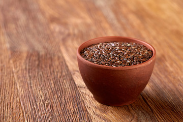 Flax seeds in wooden bowl on rustic wooden background, top view, selective focus