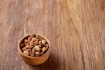 Tasty almond on a wooden plate over wooden background, top view, close-up, selective focus.