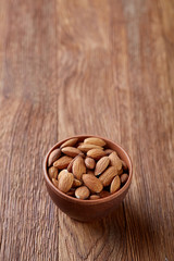 Tasty almond on a wooden plate over wooden background, top view, close-up, selective focus.
