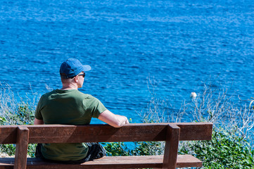 Traveler on a bench on a mountain, in a picturesque place by the sea.