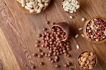 A composition from different varieties of nuts in a wooden bowls on rustic background, close-up, shallow depth of field
