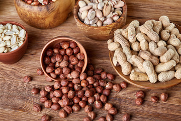 A composition from different varieties of nuts in a wooden bowls on rustic background, close-up, shallow depth of field