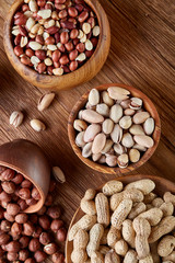 A composition from different varieties of nuts in a wooden bowls on rustic background, close-up, shallow depth of field