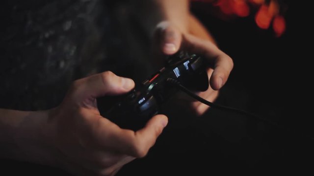 Man playing with a videogame controller in his hands. Focus on the controller