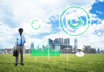 Camera headed man standing on green grass against modern cityscape