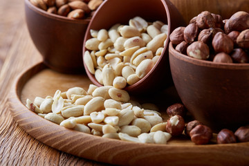 A composition from different varieties of nuts in a wooden bowls on rustic background, close-up, shallow depth of field