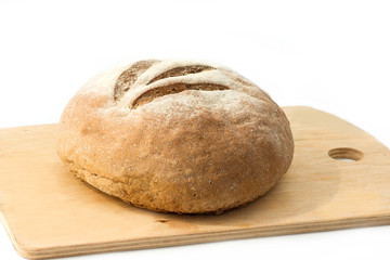 Fresh baked organic bread close-up on wooden board isolated on white background
