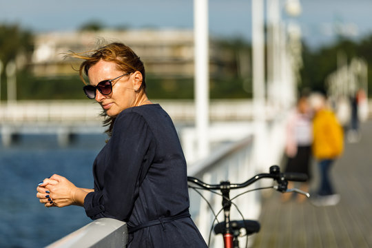 Woman relaxing with bike on pier