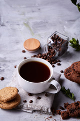 Morning coffee in white cup, chocolate chips cookies on homespun napkin, close-up, selective focus