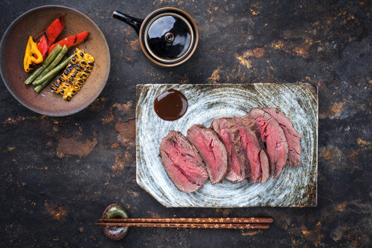 Japanese barbecue wagyu aged fillet steak with vegetable slices as top view on a plate
