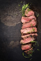 Poster Barbecue wagyu point steak slices with lettuce and herbs as top view on a board with copy space left © HLPhoto