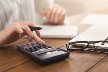 Closeup of woman hands counting on calculator