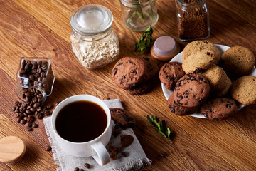 Morning coffee in white cup, chocolate chips cookies on homespun napkin, close-up, selective focus