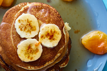 Pile of homemade pancakes with banana and walnuts on blue background, selective focus