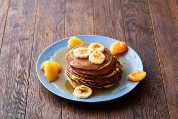 Pile of homemade pancakes with banana and walnuts on blue background, selective focus