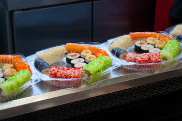 A different assortment of sushi rolls in plastic containers on the counter in the supermarket