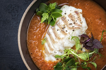 Traditional French fish soup with codfish as top view in a bowl