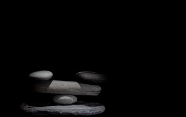 Stones in balance under a soft light on a black background