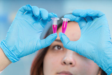 Female medical worker compares test tubes with biological samples