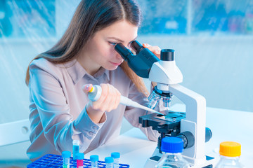  laboratory assistant with a pipette and a microscope in the laboratory