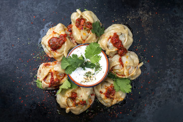 Traditional Kazakh manti steamed with mincemeat and tomato paprika salad as top view on a plate