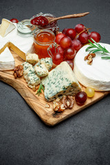 various types of cheese and jam on wooden cutting board