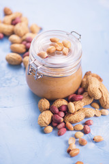 Natural peanut butter with oil in a glass jar and peanuts