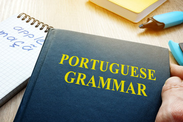 Learn portuguese grammar. Hand is holding book.