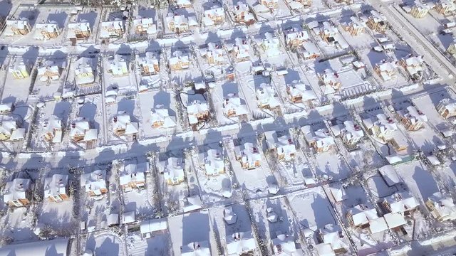Winter cottage village aerial landscape. Houses in snowy country village drone view. Luxury villa on snow background view from above flying drone.