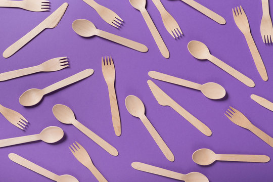 Many wooden spoons on purple background, top view