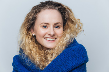 Candid shot of pleased attractive female has appealling appearance, healthy pure skin, has broad smile on face, being in good mood after date with boyfriend, isolated over light blue background