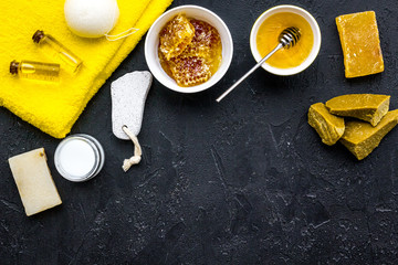Honey spa set with natural honey, soap, cream, towel and pumice stone on black background top view...