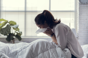 The businessman is unable to work, she is sick and sneezing heavily in bed.