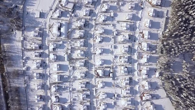 Cottage village on winter landscape aerial view. Houses in country village drone view. Luxury villa on snow background view from above flying drone.