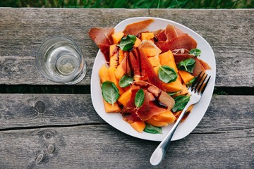 Prosciutto and melon salad with basil and balsamic sauce.