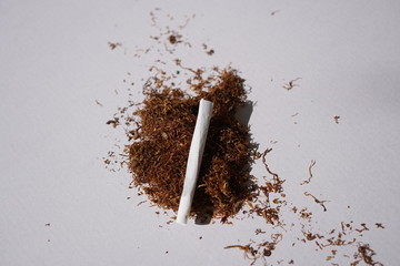 Heap of herbal smoking blend and a rolled joint on white background