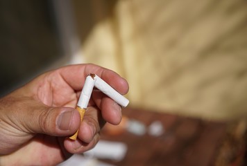 Quit smoking: human hand tearing in half a cigarette