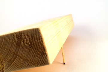 A thick wooden board supported by a thin match.