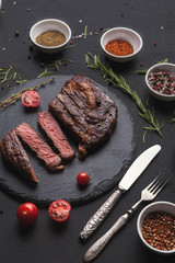 Rib eye steak and spices on black background