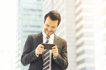 Bearded businessman using smartphone for entertainment to release his stress and for business communication to work on mobile as innovation lifestyle. Smiling face, feeling happy when get a feedback